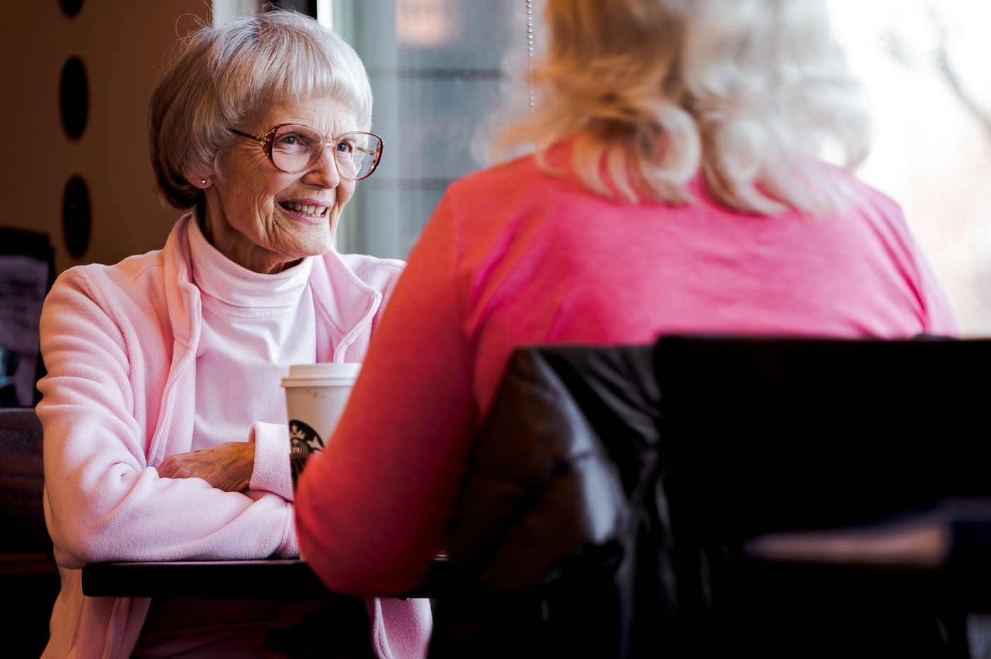 Two older women sharing a conversation over coffee