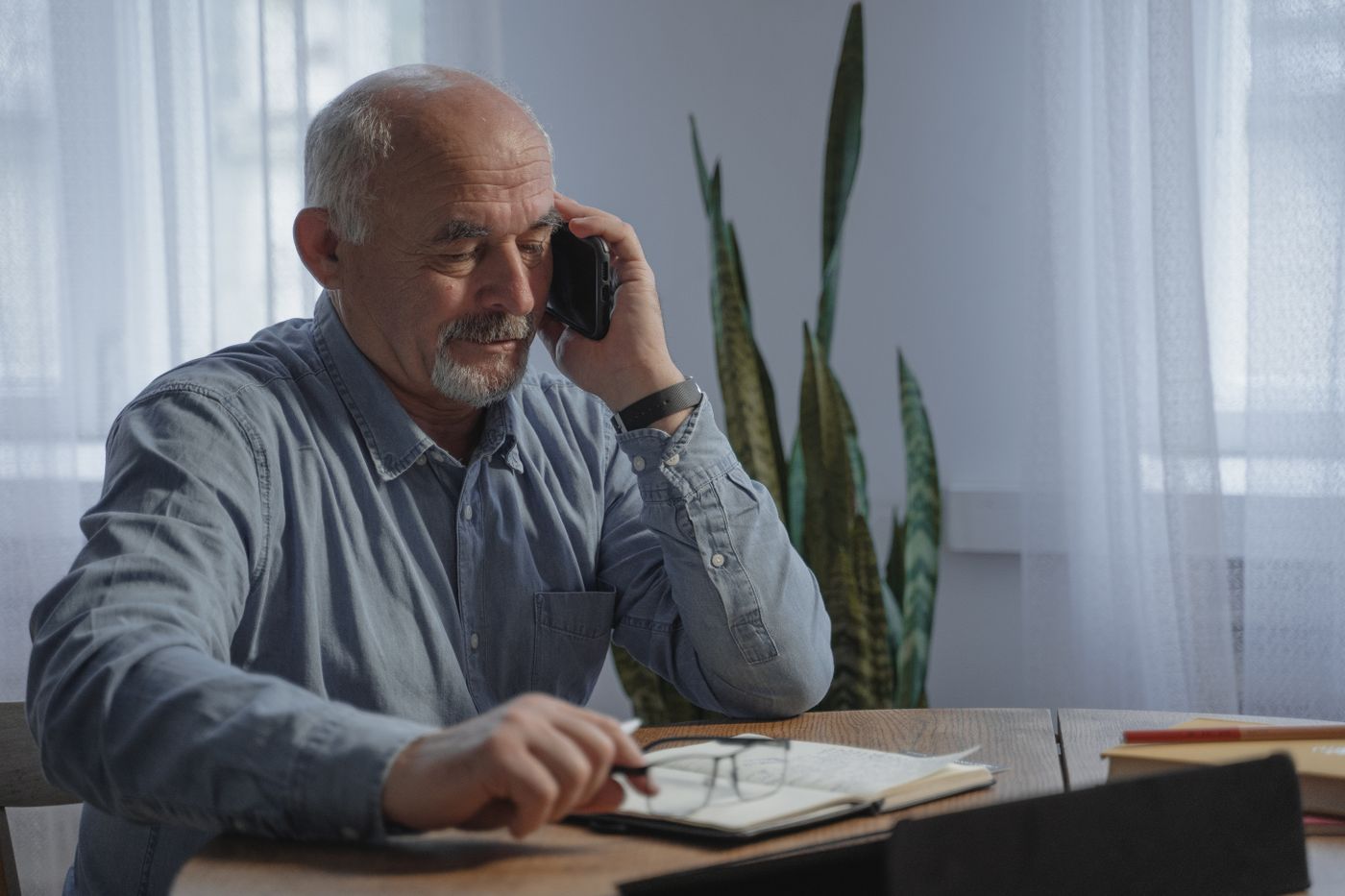 An older man listening on a phone call at home
