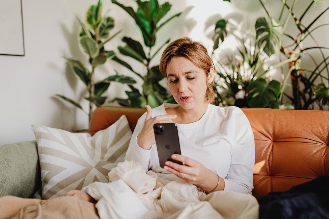 A woman having a quiet phone conversation from her sofa at home