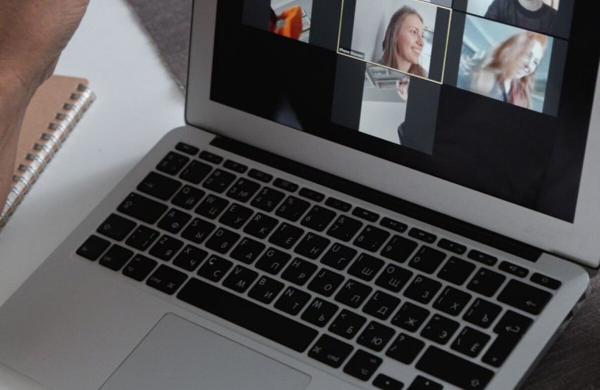 A person joins a small group video call on a laptop with notes nearby